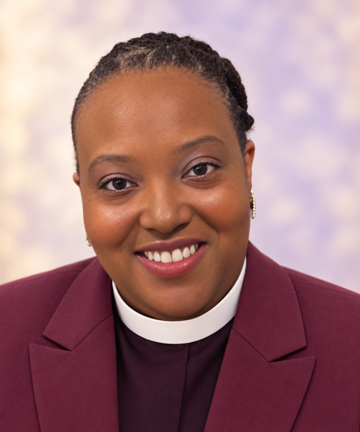 Dani Dow-Little, wedding officiant, smiling in a burgundy blazer and clerical collar